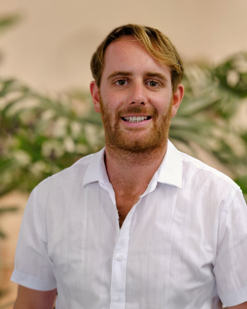 Sam from frondli, smiling in front of indoor plants